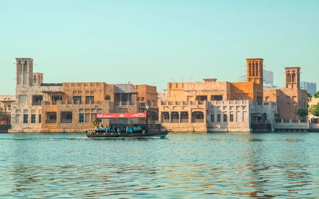 Houten abra-watertaxi op Dubai Creek voor de zandkleurige gebouwen met windtorens van Al Fahidi