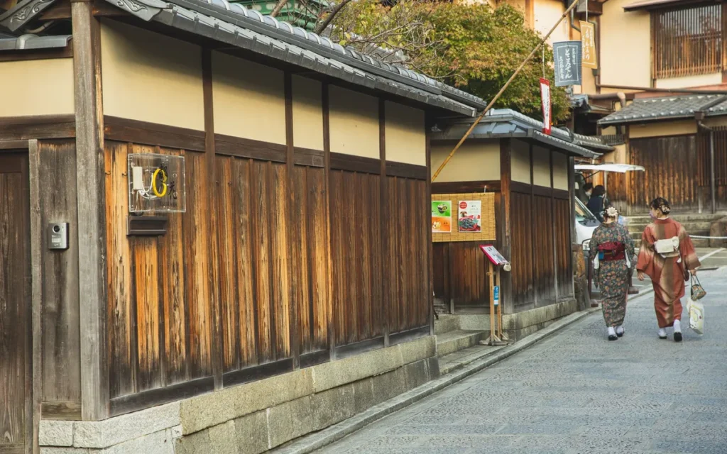 Twee vrouwen in kimono lopen door een oude straat met houten gevels in Kyoto