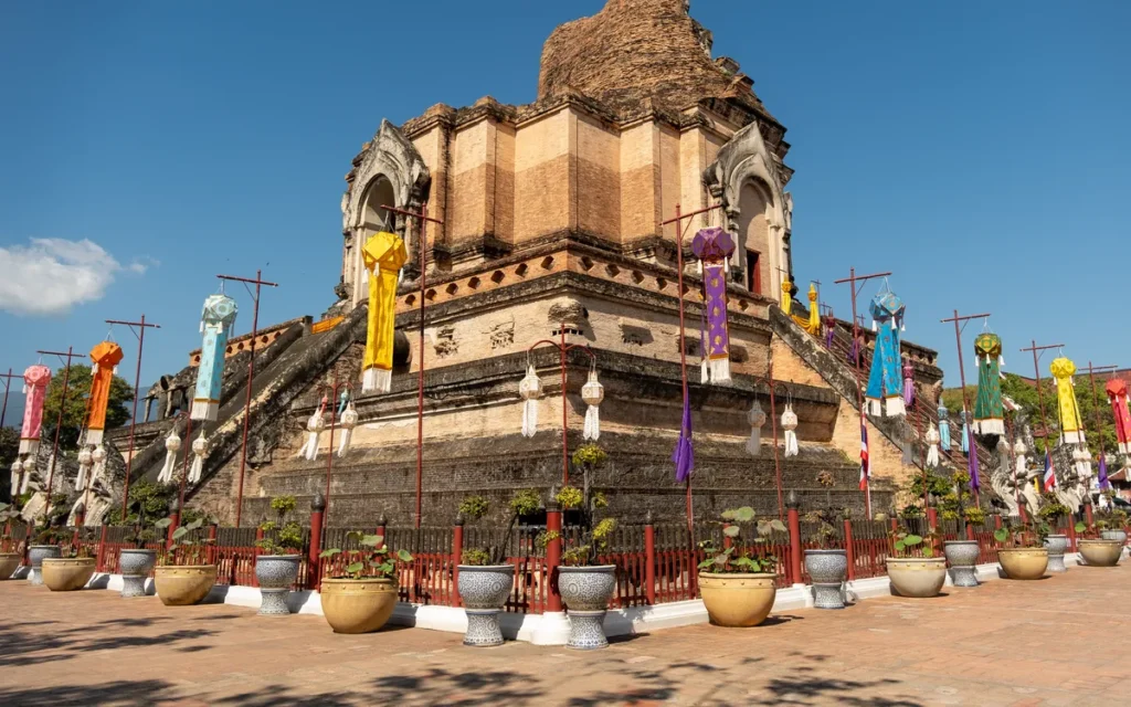 De half ingestorte bakstenen chedi van Wat Chedi Luang met kleurrijke vlaggen in Chiang Mai