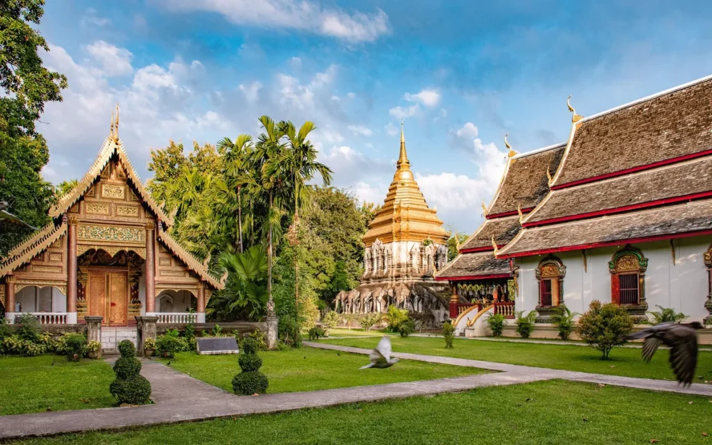 Gouden chedi en houten tempelgebouwen van Wat Chiang Man in Chiang Mai omringd door palmbomen